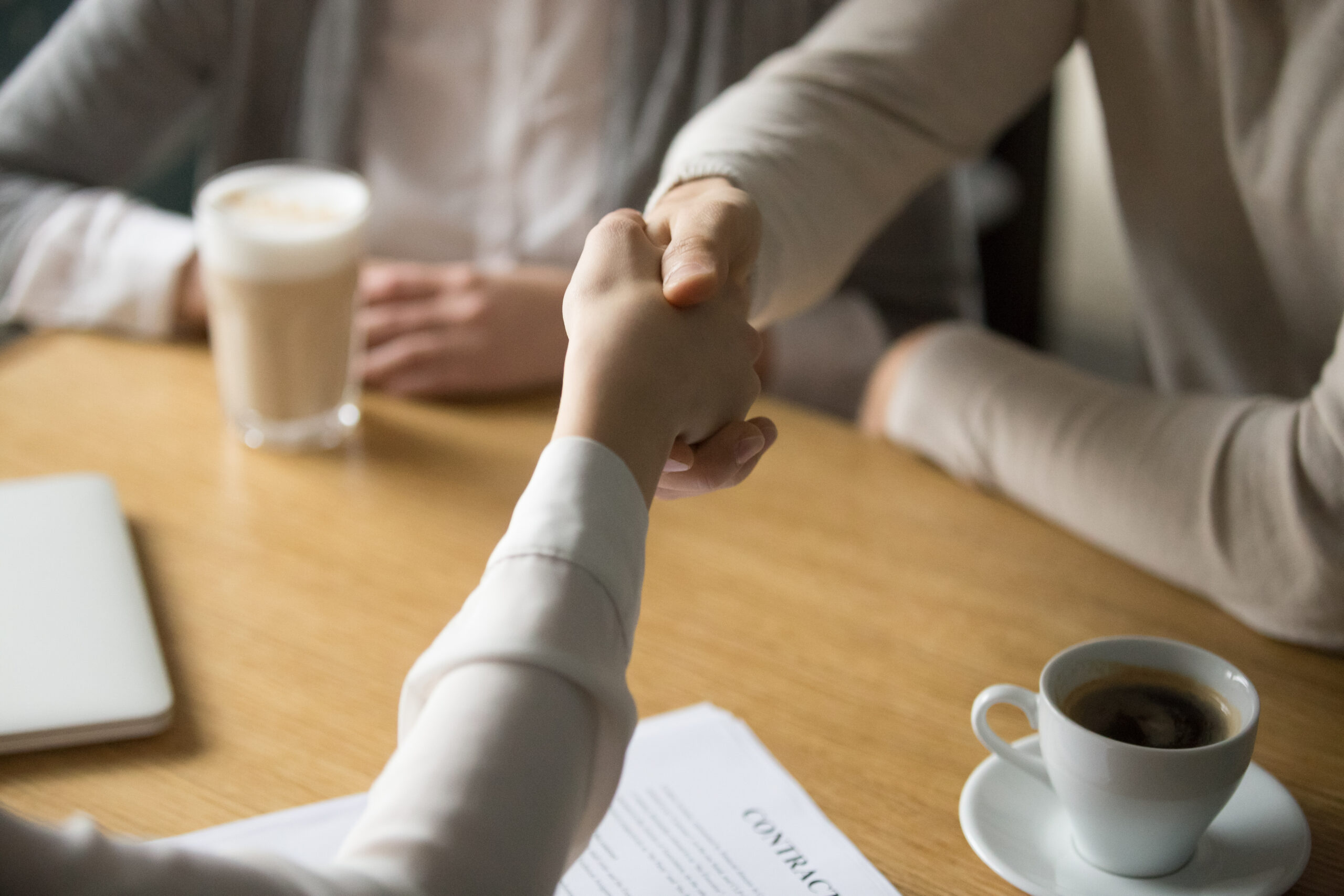 Couple handshaking businesswoman making investment deal in cafe, clients customers agree to sign contract shaking hands with mortgage insurance broker, estate agent or lawyer, close up view